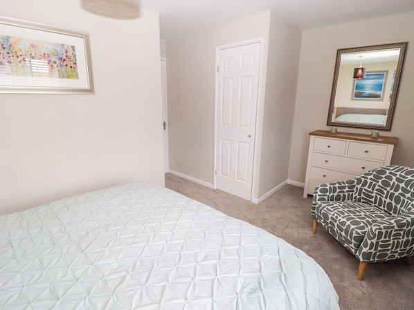 A bedroom with a bed, a dresser, a chair, a door, and a framed picture on the wall.