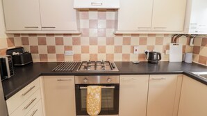 Una cocina con estufa a gas, horno y cafetera.