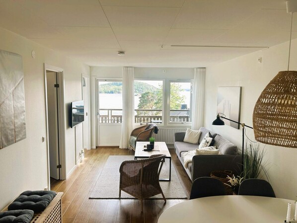 En moderne stue med sofa, spisebord og udsigt til en balkon.