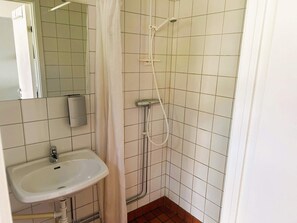 A bathroom with a sink, a shower, and a mirror.