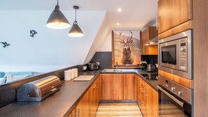 A modern kitchen with wooden cabinets, a built-in oven, a microwave, and pendant lights. - Stunning private villa for 6 people with WIFI, TV, terrace, pets allowed and panoramic view (Invergarry)