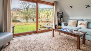 A living room with a large sliding glass door, a sofa, a coffee table, and a bookshelf. - Stunning private villa for 6 people with WIFI, TV, terrace, pets allowed and panoramic view (Invergarry)