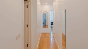 A narrow hallway with wooden flooring, white walls, and a door on the left. - 3-bed Flat Near Oxford Circus Sleeps 6 AC (London)