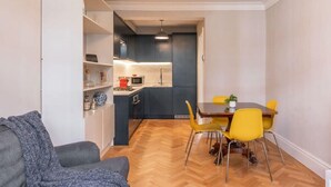 A compact living space with a kitchenette, dining area, and a sofa. - A Regal Abode - Marylebone - by Frankie Says (London)