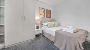 A bedroom with a bed, bedside tables, a wardrobe, and two framed pictures on the wall. - Comfy 1-bed in Soho, Steps From Carnaby Street (London)