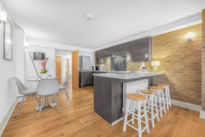 Une cuisine moderne dotée d’un îlot central, de tabourets de bar et d’un coin repas avec une table et des chaises.