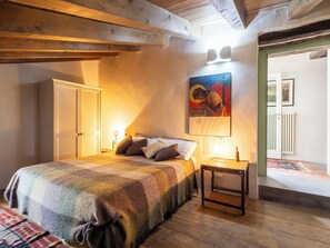 A bedroom with a bed, bedside table, lamp, and a painting on the wall.