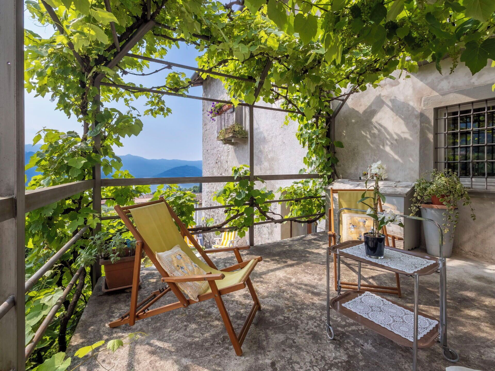 Un balcon avec une chaise en bois, une petite table et des plantes en pot.