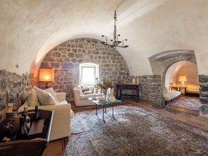 Un loft chaleureux avec des murs en pierre, une cheminée, un canapé, une table basse et un lustre.