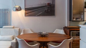 Ein moderner Essbereich mit einem runden Holztisch, weißen Stühlen und einem gerahmten Foto einer Brücke.