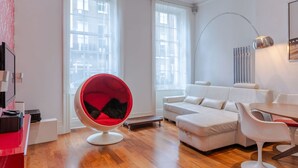 Ein modernes Wohnzimmer mit einem roten Sessel, einem weißen Sofa und einem Essbereich.