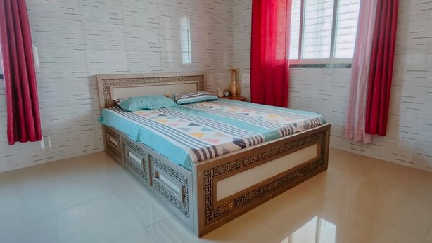 A bedroom with a bed, curtains, and a patterned wall.