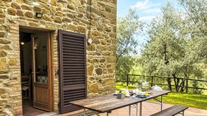 Un edificio de piedra con puerta de madera y mesa de patio con bancos.