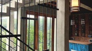 A staircase with metal railings, a brick wall with a bar area, and a view of greenery outside.
