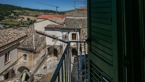A view of a traditional stone building with a tiled roof, a balcony, and a construction crane in the background.