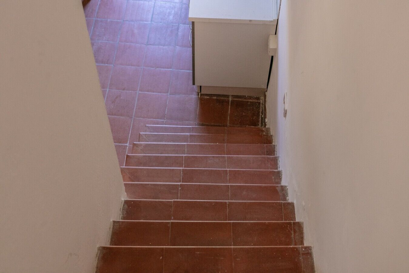 A staircase with brown tiles leading to a white door.
