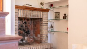A fireplace with a brick design, a wooden mantel, and a shelf with decorative items.
