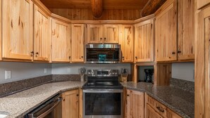 Una cocina con gabinetes de madera, electrodomésticos de acero inoxidable, encimeras de granito y lavavajillas.