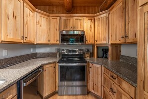 Eine Küche mit Holzausstattung, Edelstahlgeräten, Granit Arbeitsplatten und einem Geschirrspüler.