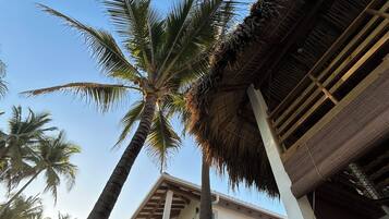 A building with a thatched roof and palm trees.