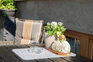 A patio table with a clear ashtray, a decorative frog figurine, and a welcome sign. - Appartement Neumayer (Viehhofen)