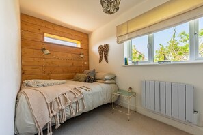 Ein Schlafzimmer mit hölzernem Kopfteil, einem Fenster mit Aussicht, einer Heizung und einem Nachttisch.