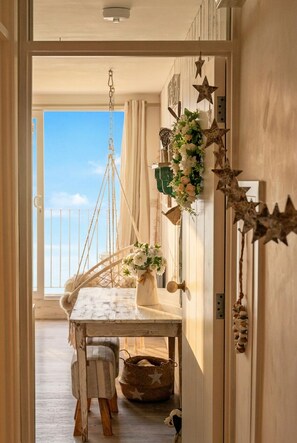 Ein Zimmer mit einem rustikalen Holztisch, einem Hängesessel, einer Wand mit Sternornamenten und Blick zum Himmel durch eine Tür.