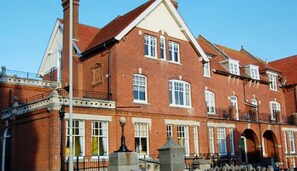 A red brick building with multiple windows, a balcony, and a stone entrance. - Bright 2‑Bed Apartment with Balcony, Sea Views & Parking in Central Swanage (Swanage)