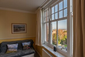 A room with a large window, a framed picture on the wall, and a sofa with cushions. - Bright 2‑Bed Apartment with Balcony, Sea Views & Parking in Central Swanage (Swanage)