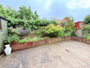 Ein Garten mit einer Backsteinmauer, einer weißen Vase und verschiedenen Pflanzen.