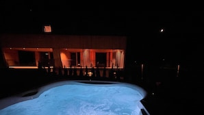 Una piscina de noche con un edificio al fondo.