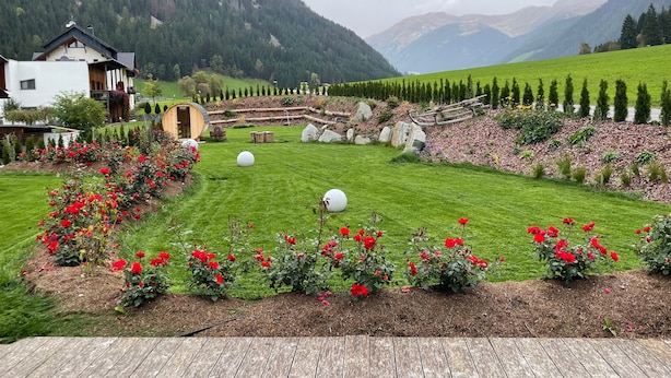 Paisaje rural con una casa, una terraza de madera y un campo de rosas rojas.