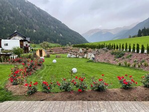Un paysage rural avec une maison, une terrasse en bois et un champ de roses rouges.