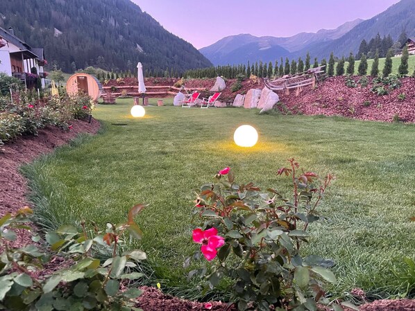 Une pelouse bien entretenue, une clôture en bois, un petit jardin fleuri et une chaîne de montagnes en arrière-plan.