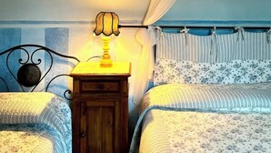Une chambre avec deux lits, une table de chevet, une lampe et un lit à baldaquin.