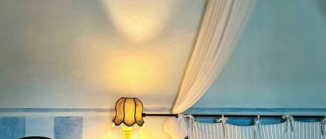 A bedroom with two beds, a nightstand, a lamp, and a canopy bed.