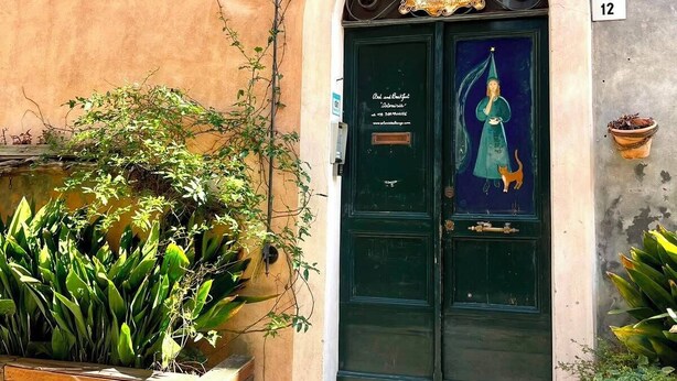 Un bâtiment avec une porte verte, une enseigne au-dessus de la porte et le chiffre « 12 » peint sur le mur.