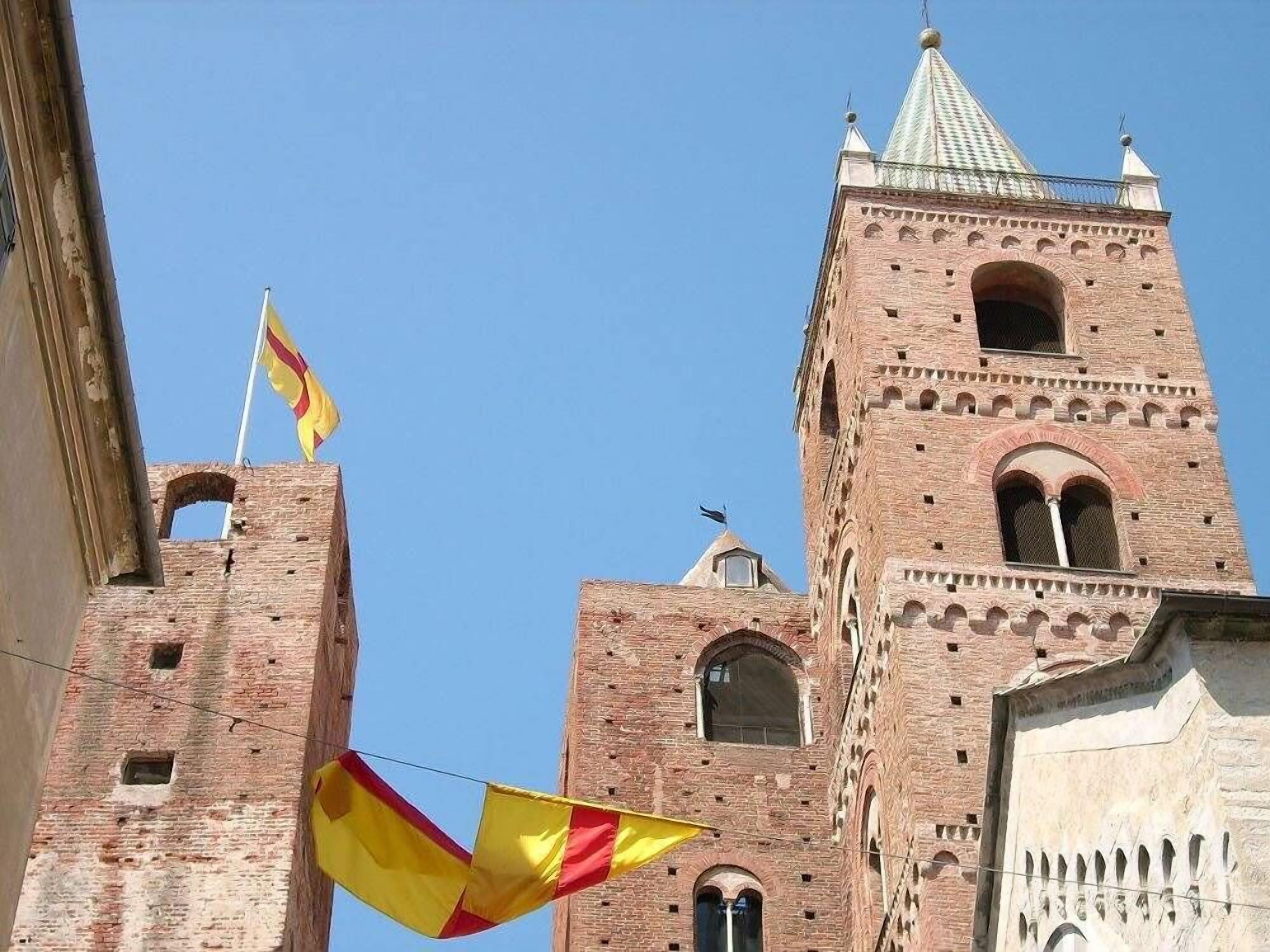Una torre de ladrillo histórico con ventanas de arco y techo puntiagudo.