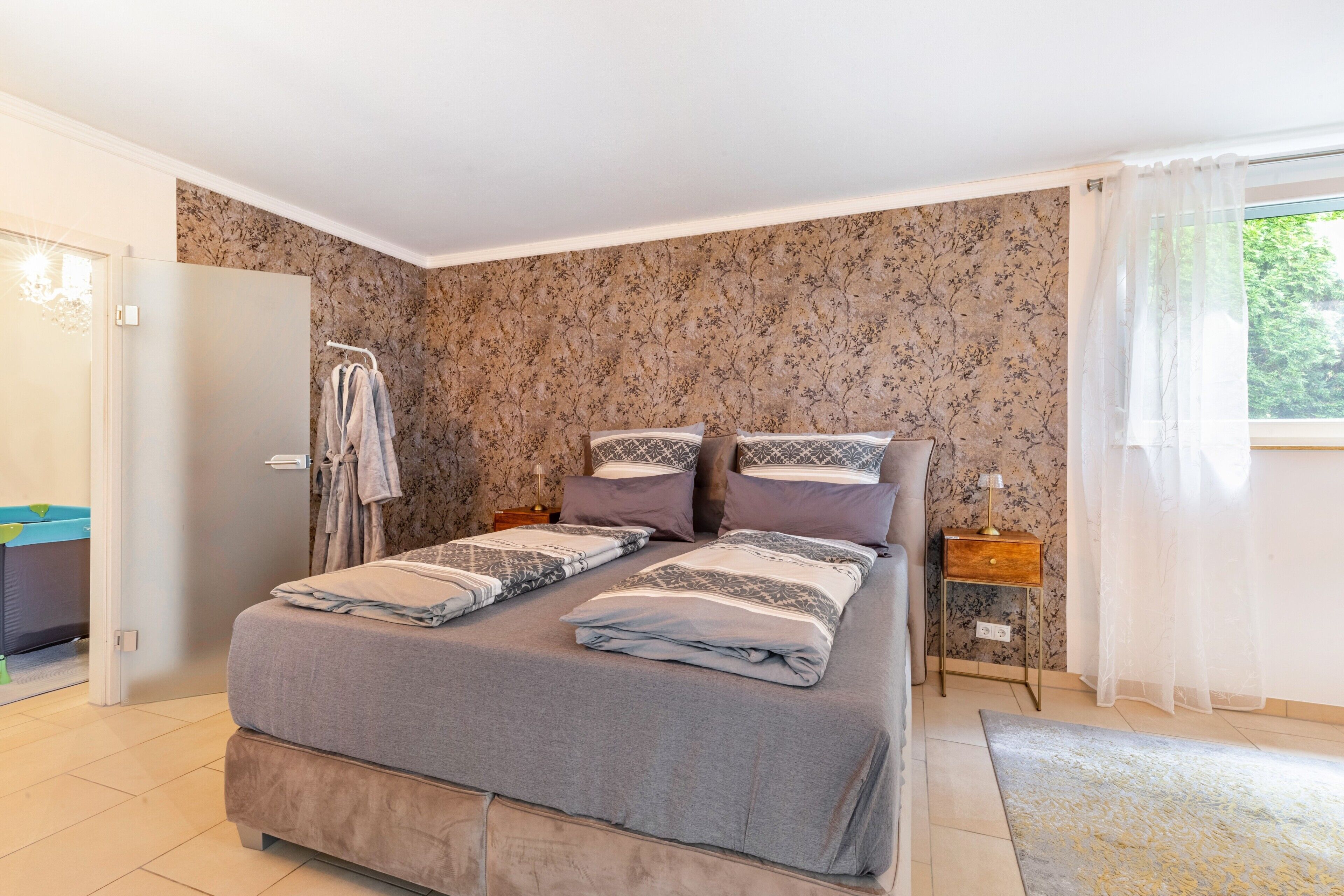 Une chambre à coucher avec un lit, une table de chevet, une armoire et une fenêtre avec des rideaux.