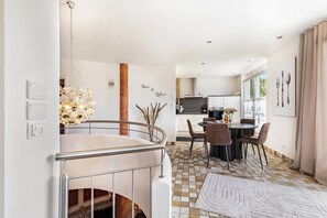 Un intérieur moderne comprenant un escalier, un coin repas, une cuisine et une vue sur l’extérieur.