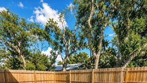 A rectangular swimming pool with clear blue water, surrounded by a wooden fence, and a tiled deck area with lounge chairs. - Private Pool • Walk to St. Augustine Beach (St. Augustine)