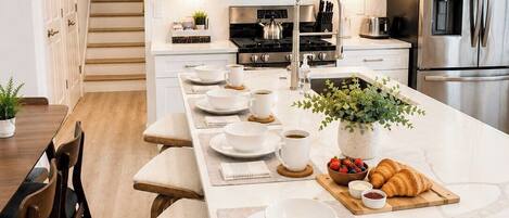 A modern kitchen with white cabinetry, stainless steel appliances, and a central island with seating.