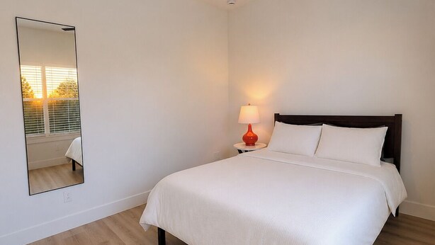 A bedroom with a bed, a ceiling fan, a bedside lamp, a mirror, and a window with blinds. - Private Pool • Walk to St. Augustine Beach (St. Augustine)