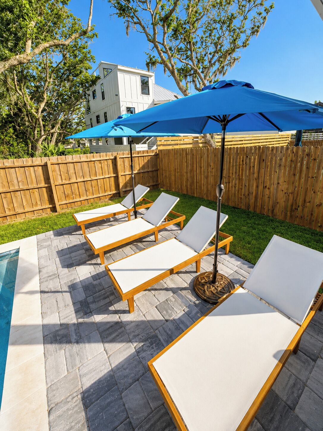 Un espace aménagé au bord de la piscine, avec des chaises longues et un parasol bleu.
