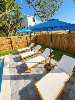 Ein Poolbereich mit Liegestühlen und einem blauen Sonnenschirm.