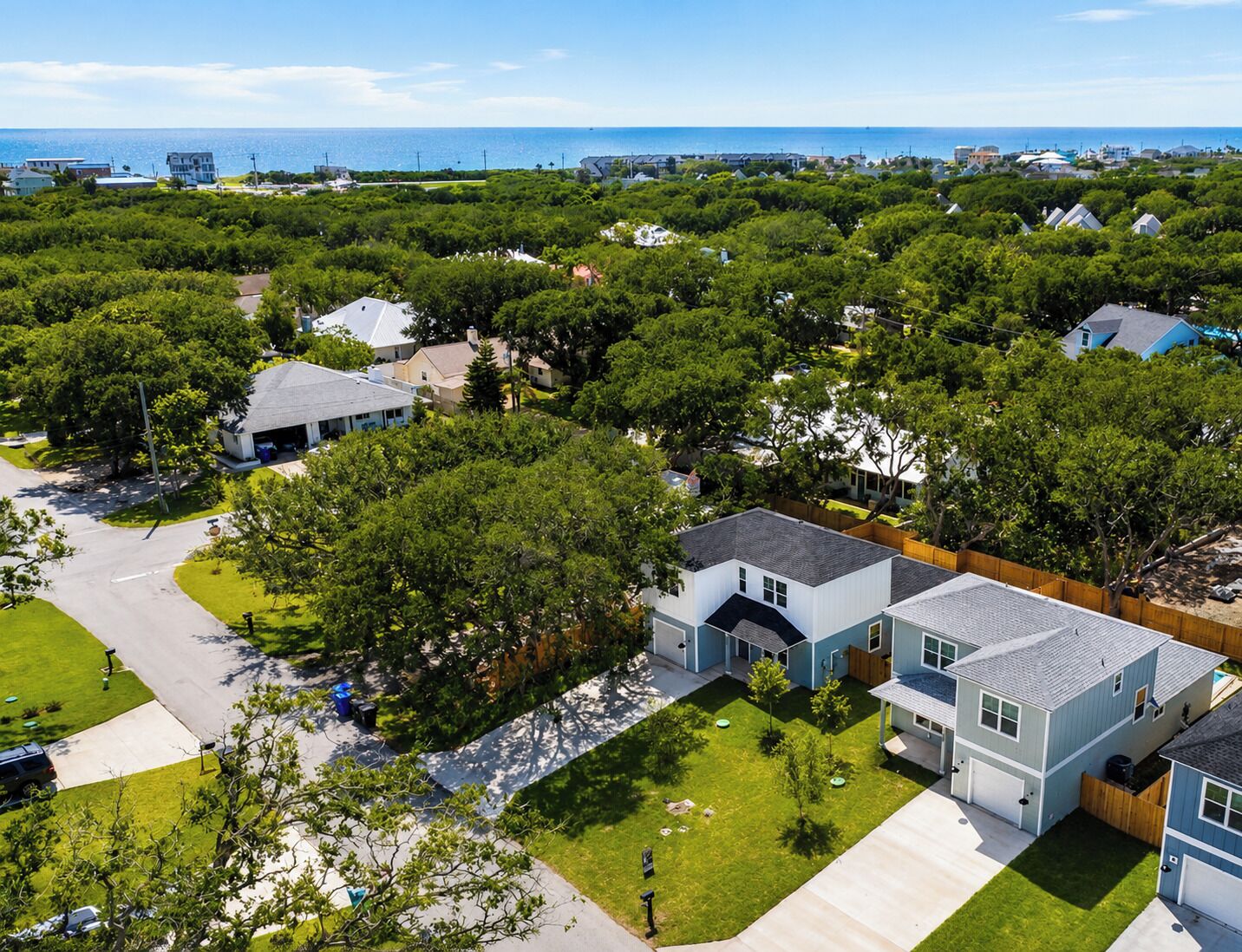 Un quartier résidentiel avec des maisons, une allée et une vue sur l’océan.