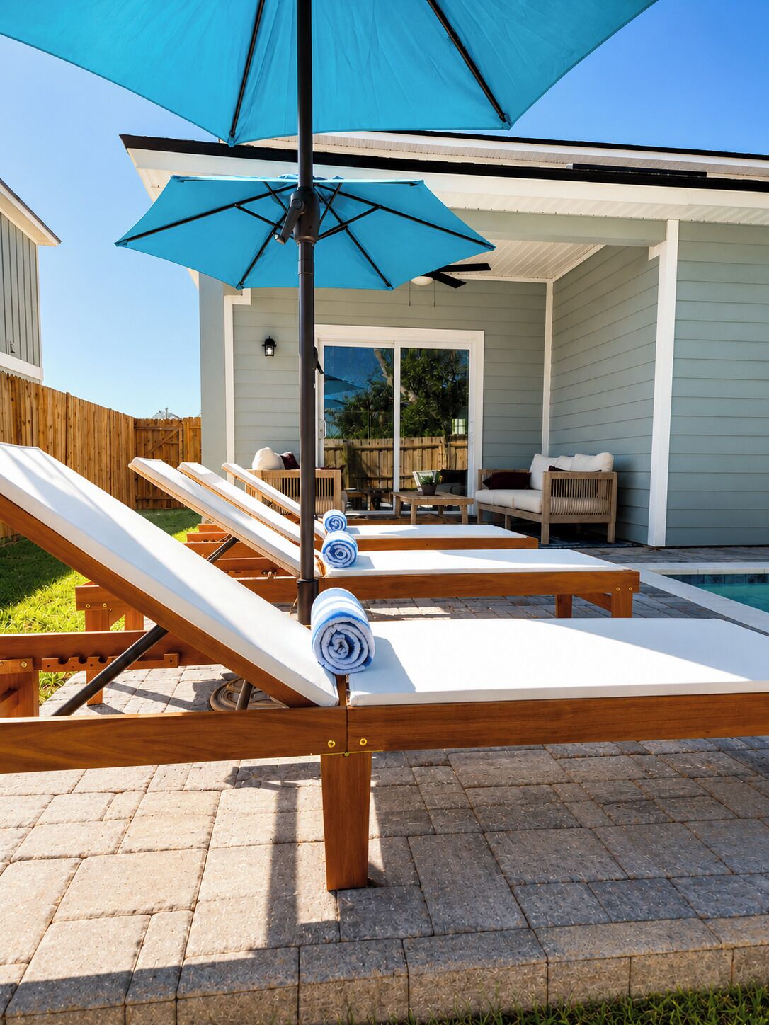 A poolside area with lounge chairs and a blue umbrella.