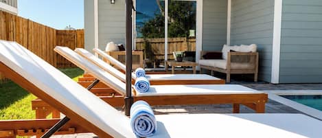 A poolside area with lounge chairs and a blue umbrella.