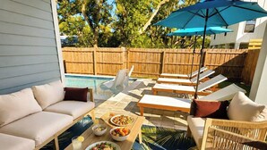 Um alpendre coberto com piscina, área de estar e mesa de jantar.