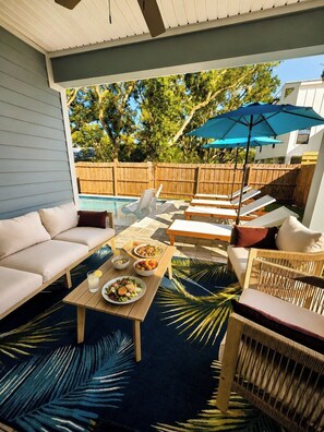 Eine überdachte Terrasse im Freien mit Pool, Sitzbereich und Esstisch.